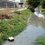 Lixeiras clandestinas prejudicam serviço de limpeza da cidade - Na Luzia: lixo e caixa coletora ao fundo